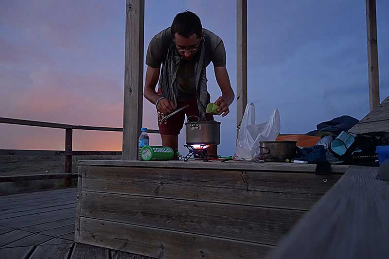 Das Kochen mit Benzinkocher im Sonnenuntergang