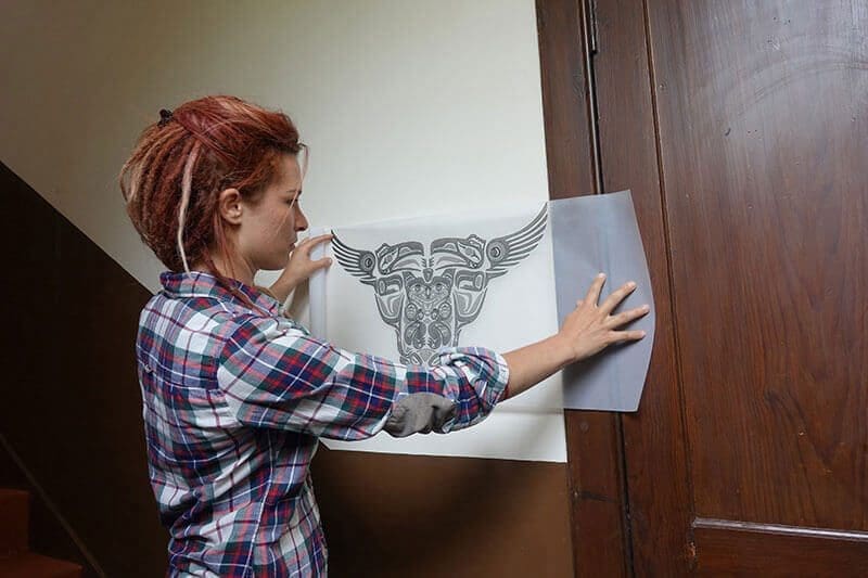 Shania hält eine Tattoovorlage an die Wand