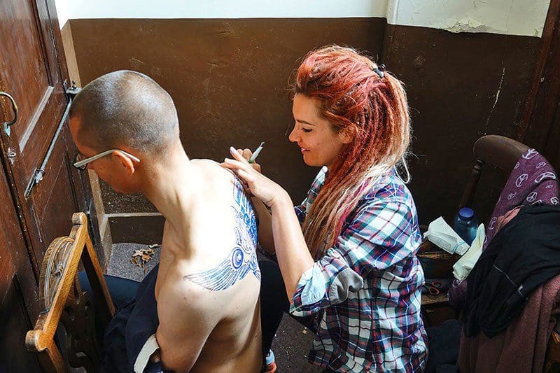 Vorbereitung eines rituellen Tattoos - Shania malt die Tattoo-Vorlage auf den Rücken von Franz