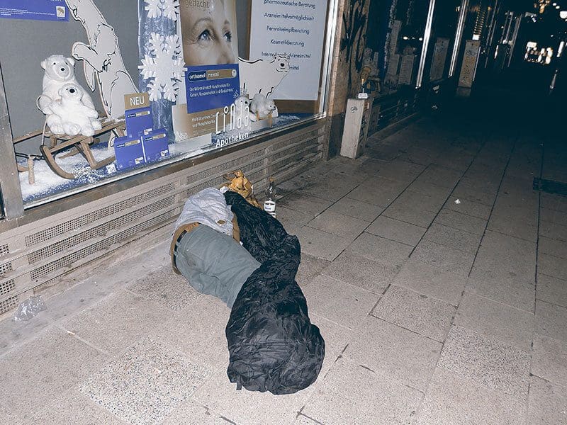 Ein Obdachloser liegt schlafend auf der Straße