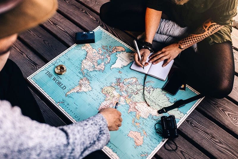 Eine Weltreise planen Noitzen Büro Landkarte besprechen
