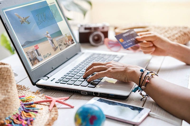 Mit der richtigen Reise Kreditkarte werden Flüge und Urlaub online mit einem Laptop gebucht.
