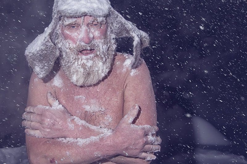 Mann steht nackt im Schnee, mit Saunahut auf dem Kopf