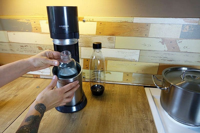Die mit Leitungswasser befüllte SodaStream Glasflasche wird für die Zubereitung in das Gerät begeben.