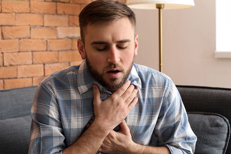 Asthmatiker hält sich die Hände an den Brustkorb