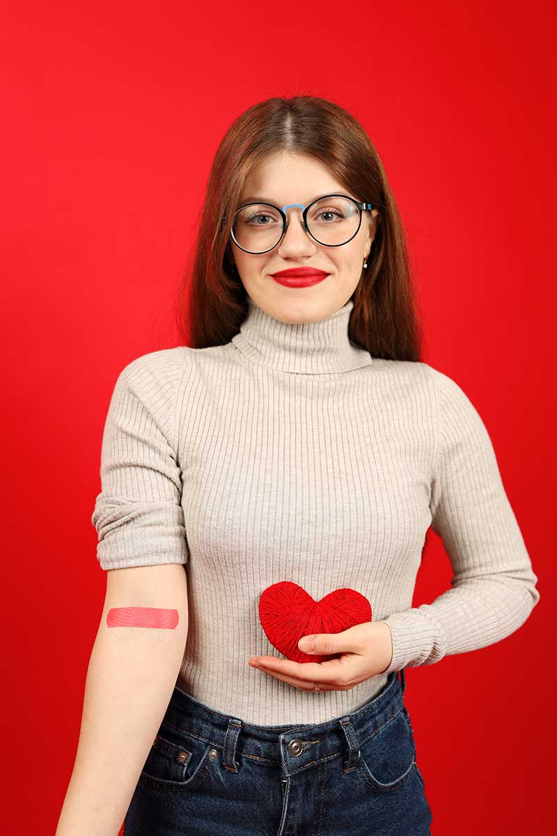 Frau hält ein Herzsymbol in der Hand nach Blutabnahme
