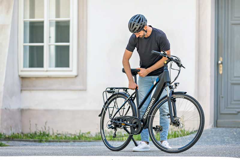 Mann verstellt Sattel bei e bike von Grundig