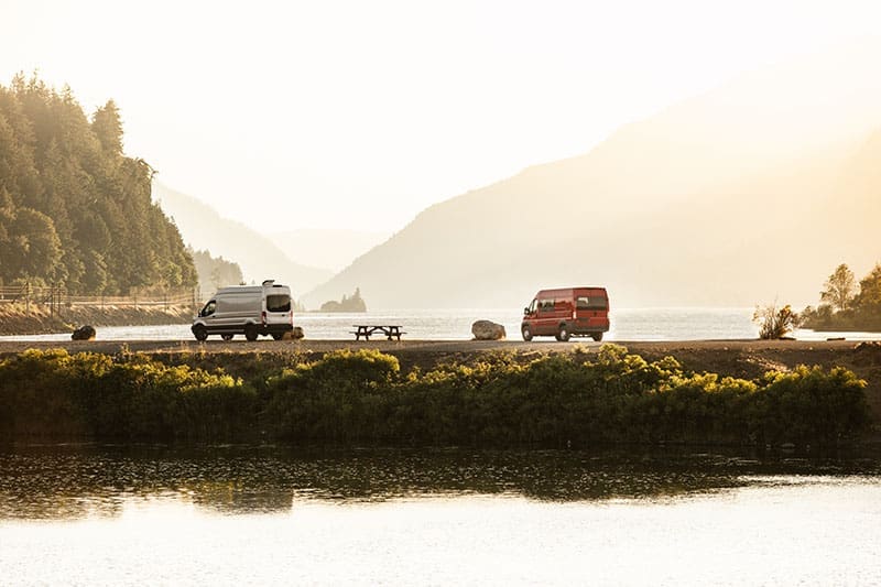 Vanlife mit Autos am Wasser in der Natur parkend