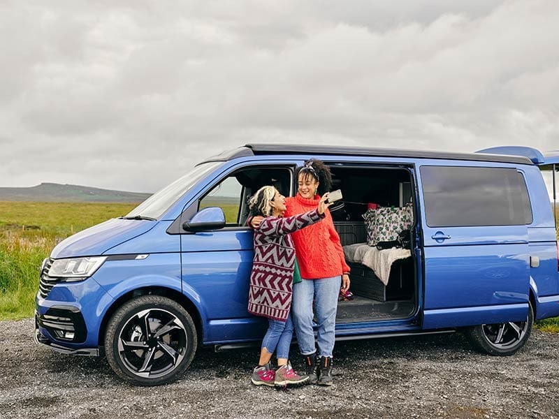 Frauen-machen-ein-Foto-vor-einem-Van-Camper