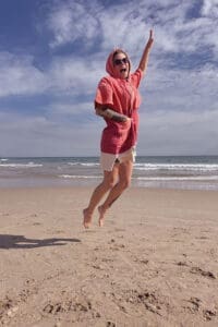 Shania-hüpft-im-Poncho-von-Wave-Hawaii-am-Strand